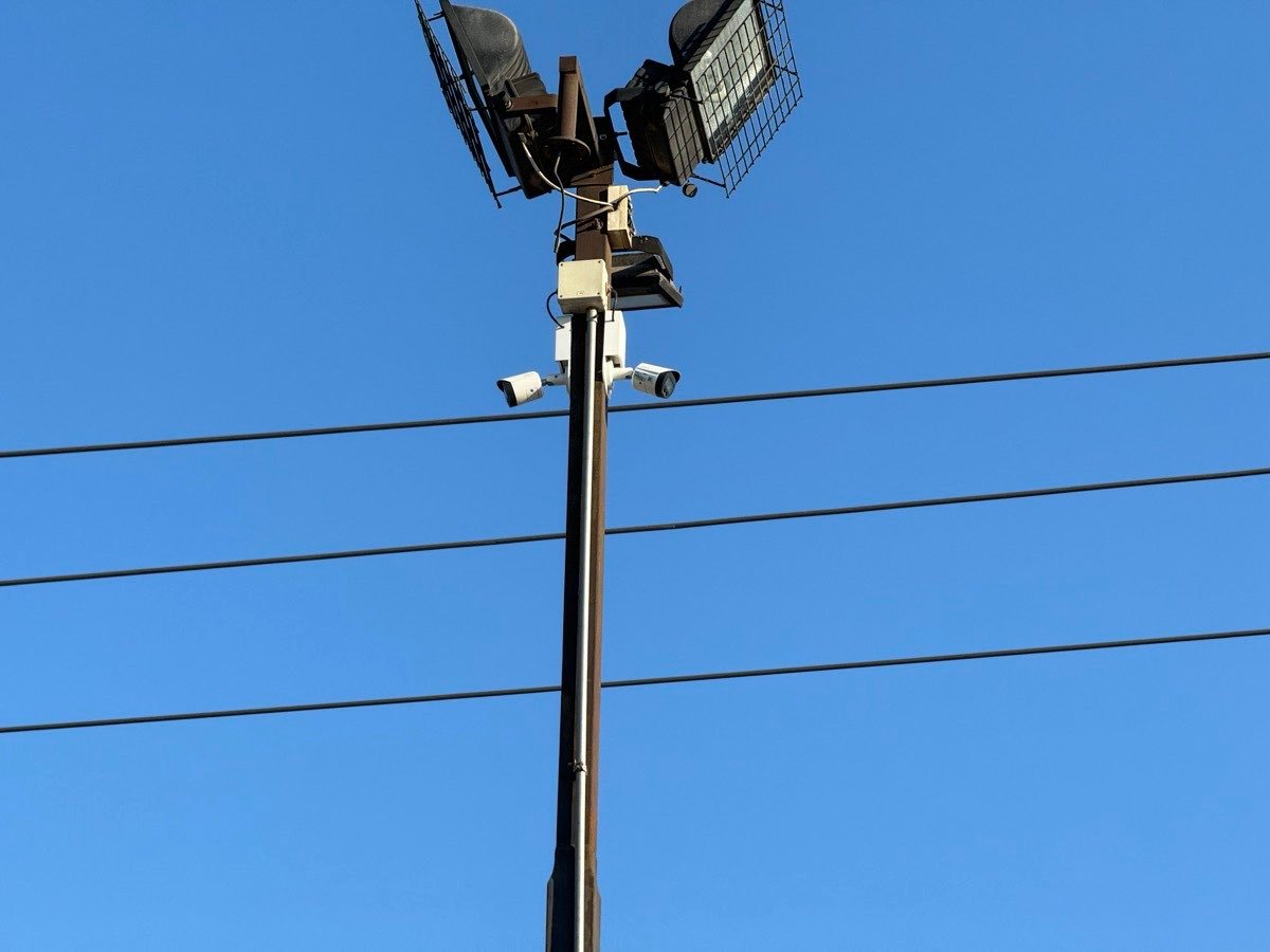 Dos cámaras bullet instaladas en un poste junto a proyectores de iluminación exterior