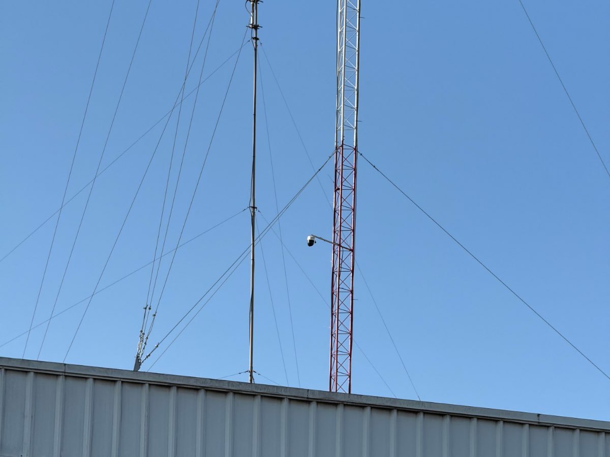 Mástil arriostrado y torre de celosía montados sobre el techo de un galpón industrial